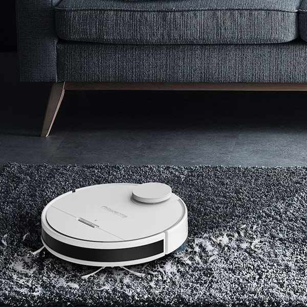 Een robotstofzuiger die een grijs tapijt in een woonkamer stofzuigt